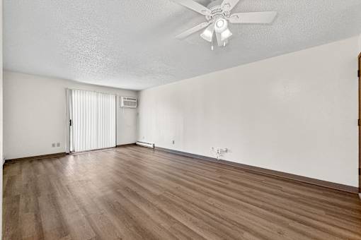 A room with a ceiling fan and wooden flooring.