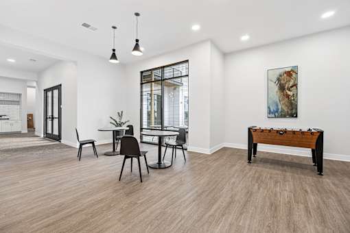 A room with a table and chairs and a painting on the wall.