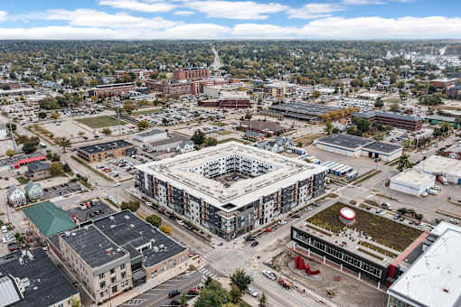 A large building with a green roof is surrounded by other buildings and construction.