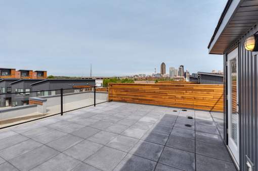 A rooftop patio with a wooden wall and a city skyline in the distance.at 5Fifty5, Des Moines, IA 50309  