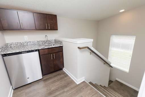 a kitchen with a sink and a bar and a staircase at 5Fifty5, Iowa  