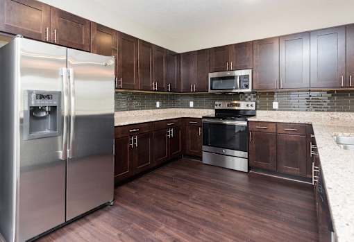 a kitchen with stainless steel appliances and wooden cabinets at 5Fifty5, Des Moines Iowa  