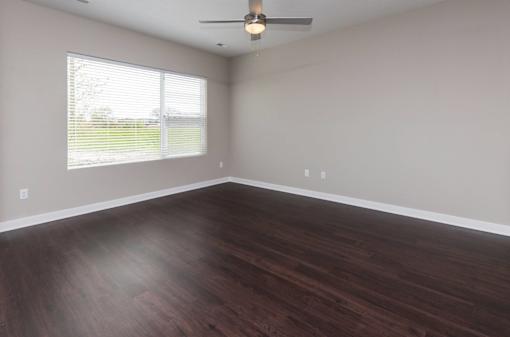 an empty living room with wood floors and a window at 5Fifty5, Iowa  