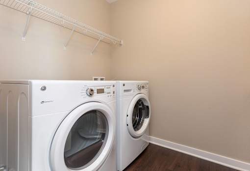 a washer and dryer in a laundry room with a rack on the wall at 5Fifty5, Des Moines, IA 50309  