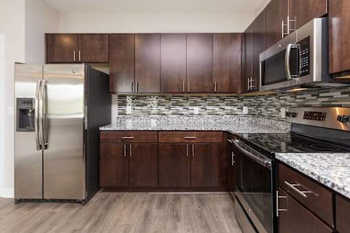 a kitchen with wooden cabinets and stainless steel appliances at 5Fifty5, Iowa, 50309