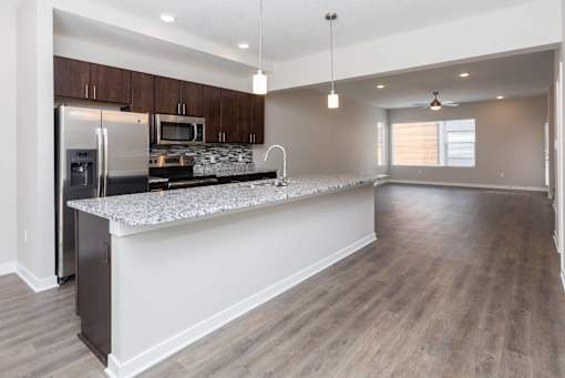 a kitchen with a large island and a stainless steel refrigerator at 5Fifty5, Des Moines, IA  