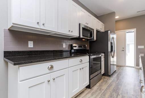 a kitchen with white cabinets and a black counter top at 5Fifty5, Des Moines Iowa  