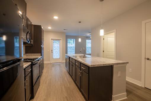 A modern kitchen with dark wood cabinets and a large island.