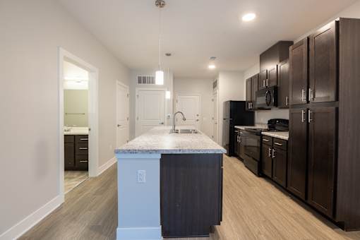 A kitchen with a marble island and dark wood cabinets.