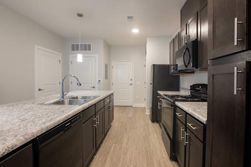 A kitchen with dark wood cabinets and a granite countertop.