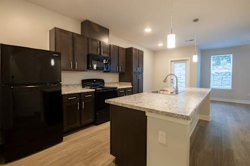 A kitchen with black appliances and brown cabinets.
