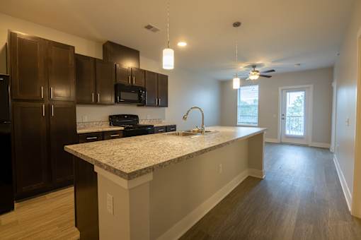 A kitchen with a granite countertop and dark brown cabinets.