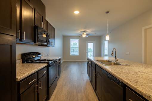 A kitchen with black cabinets and a granite countertop.