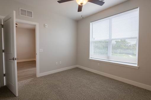 A room with a ceiling fan and a window with blinds.