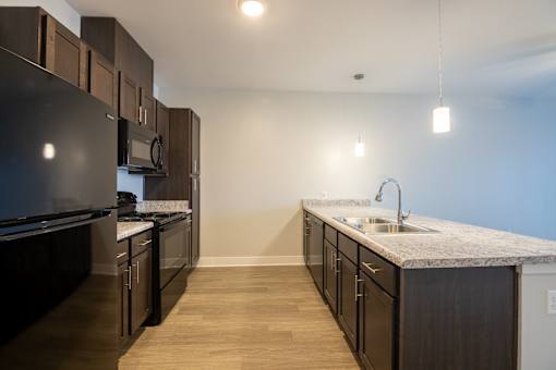 A kitchen with dark wood cabinets and a granite countertop.