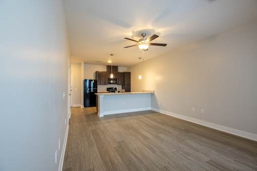 A room with a ceiling fan and a kitchenette.