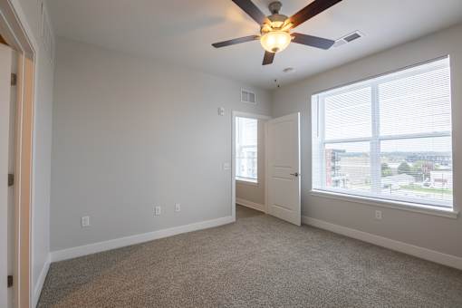 A room with a ceiling fan and carpeted floor.