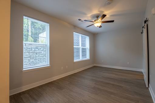A room with a ceiling fan and two windows.