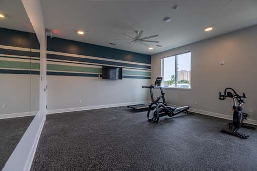 A room with a grey carpet and a ceiling fan.
