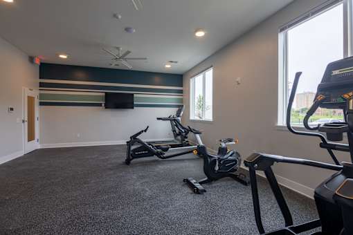 A gym with treadmills and a television on the wall.