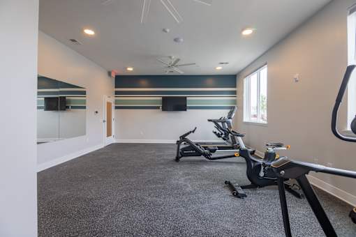 A spacious room with a grey carpet and a mirror on the wall.