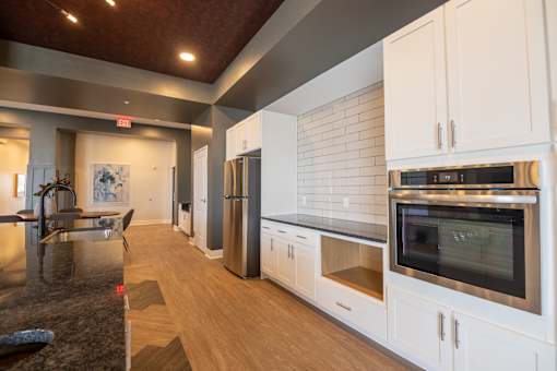 A kitchen with white cabinets and a black counter top.