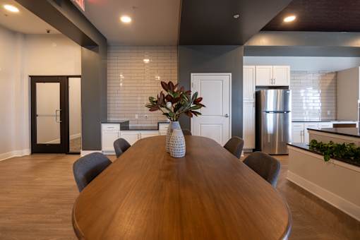 A wooden dining table with chairs and a vase of flowers in the middle.