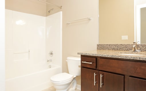 Bathroom with granite counter tops a large mirror and a bathtub at 7th Street Brownstones, Indigo Living, Iowa
