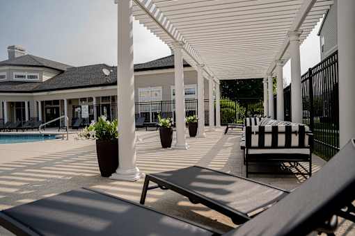A patio with a black and white striped chair and a pool in the background.at 92West, West Des Moines, IA 50266  