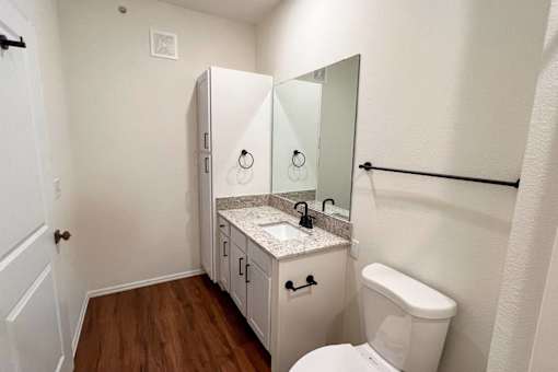 a bathroom with a toilet and a sink and a mirror at 92West, West Des Moines, IA  