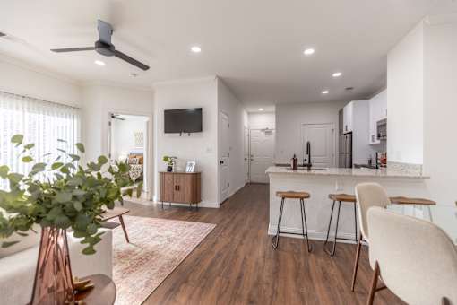 A modern kitchen with a bar stool and a plant in a vase.
