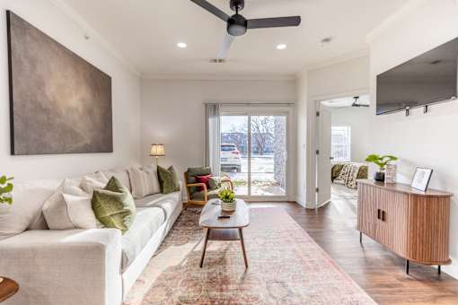 A living room with a white couch and a large painting on the wall.