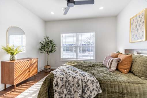A bedroom with a bed, dresser, and window.