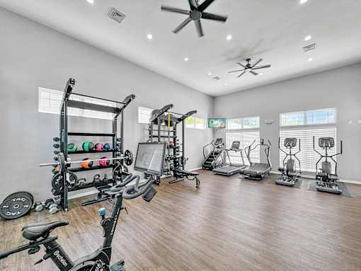 a gym with cardio machines and weights on a wooden floor at 92West, West Des Moines, IA 50266  