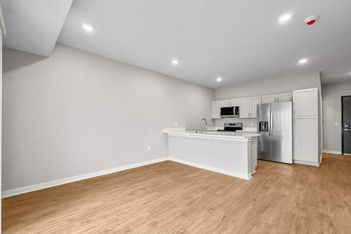 A kitchen with white cabinets and a wooden floor.