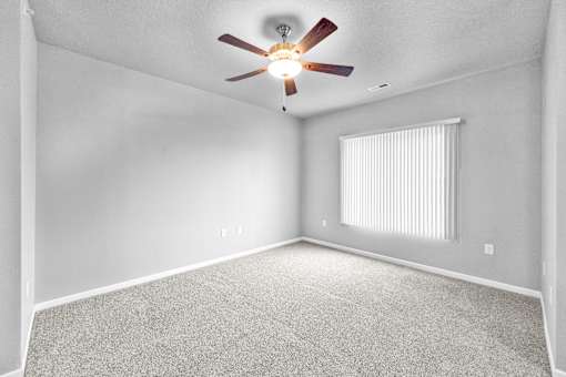 A room with a ceiling fan and a window with blinds.