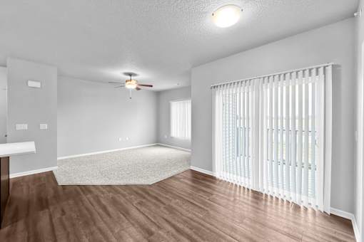 A room with a ceiling fan and a window with blinds.