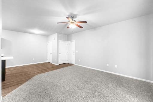 A room with a ceiling fan and a grey carpet.