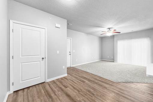 A room with a white door, a ceiling fan, and a rug on the floor.