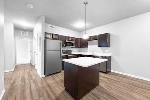 A kitchen with dark brown cabinets and a white island.
