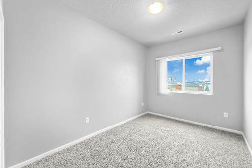 A room with a window showing a blue sky and clouds.