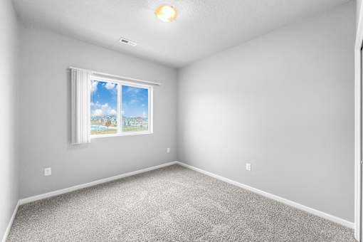 A room with a window showing a blue sky and clouds.