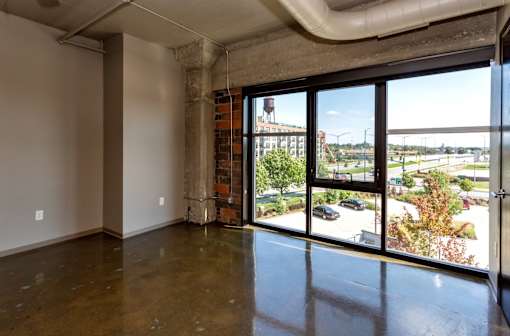 Living room with floor to ceiling windows and a city view at Ballyard Lofts, Indigo Living, IA, Iowa , 50309