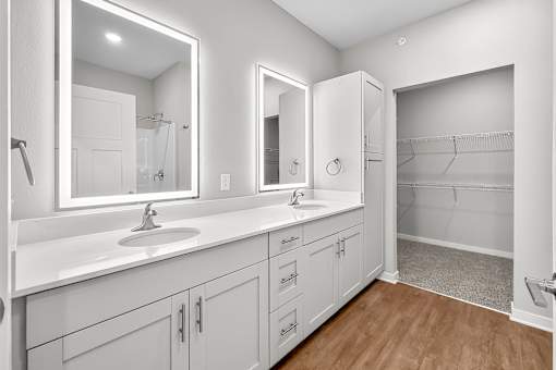 A bathroom with a double sink vanity and a walk-in shower.