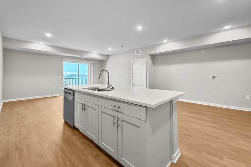 A kitchen with a white countertop and wooden floors.