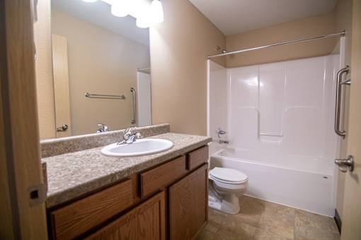 A bathroom with a sink, toilet, and bathtub.at Cottages at Johnston Commons, Iowa  