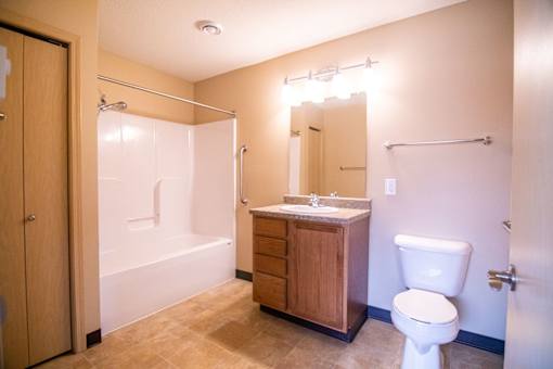 A bathroom with a toilet, sink, and shower.at Cottages at Johnston Commons, Johnston, IA  