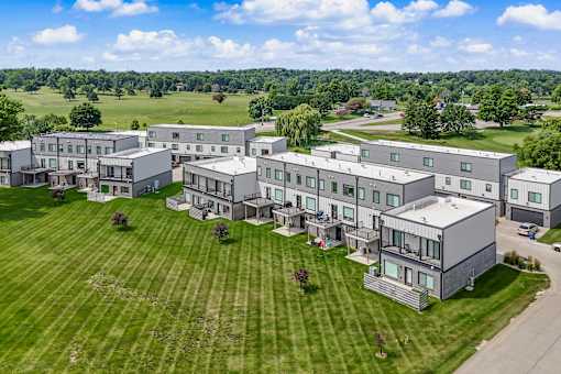 A large, modern building complex with a green lawn in front.