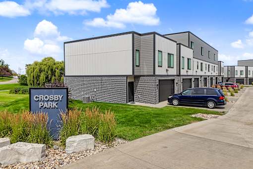 A modern building with a sign that reads "Crosby Park" in front of it.