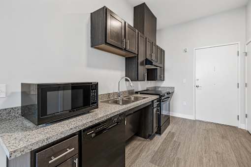 A kitchen with black appliances and brown cabinets.